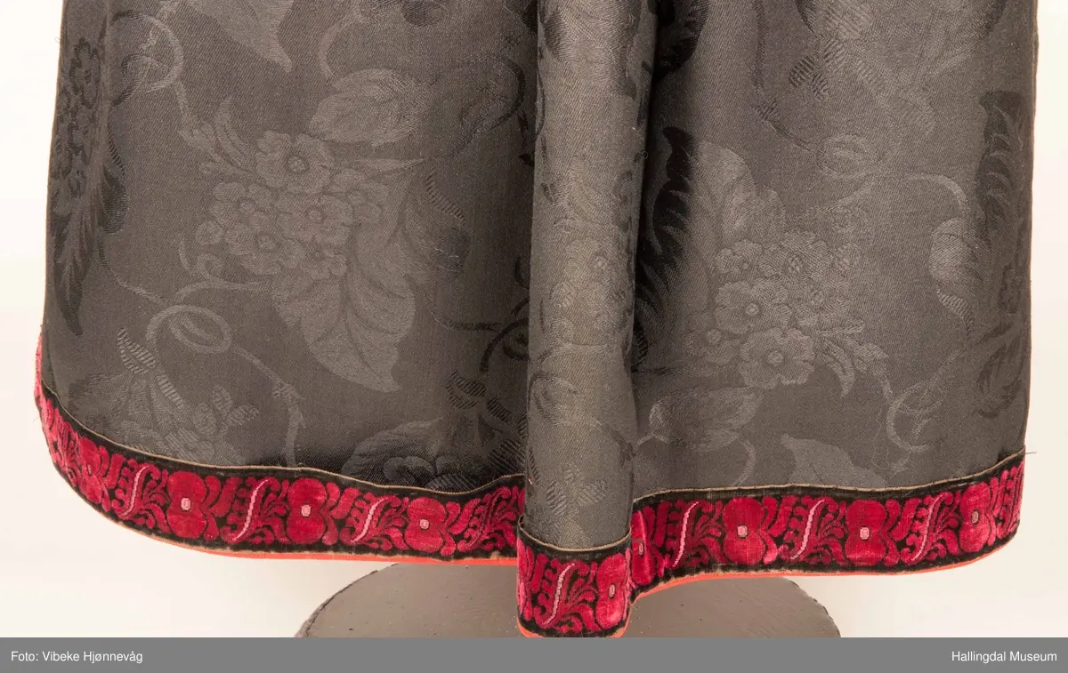 Kone fra Øvre Hallingdal i hallingbunad.  Hun bærer hette.  Kona står utstilt i den faste bunadutstillingen på Hallingdal Museum, Nesbyen.  Hallingbunaden består av mange draktdeler; trøye, Forkle HFN 02033, stakk, hette, silketørkle i halsen, perlet bringduk el. brystklut og skjorte.