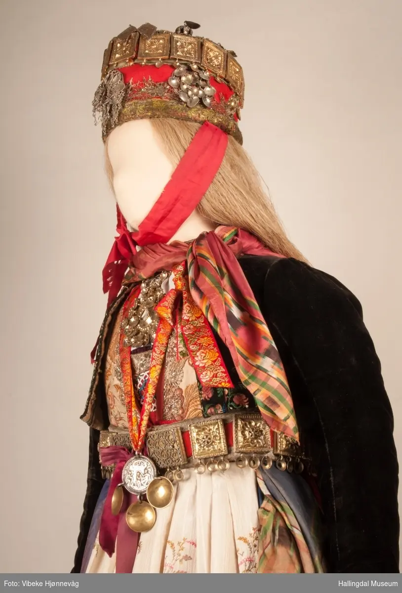 Drakten står utstilt i den faste bunadutstillingen på Hallingdal Museum, Nesbyen.  Den ble satt opp på grunnlag av et bilde fra Norsk Folkemuseum, tatt ang. av Axel Lindahl.  Tidfestet til 1877-78.  Høyde på overdel ble bestemt etter lengden på trøya.  Utelatelsen av det store bryststykket og andre forandringer ble diskutert med Ågot Noss og godkjent.  Ny dokke ble bygd opp med utgangspunkt i stakkens mål.
HFN 03387-stakk med liv.  Stakk og liv ble skilt 5.1.1999, rød ulltråd med tråklesting festet delene sammen, fjernet.  Stakk festet til liv i ny høyde med store attersting med rødt bomullsgarn.  Det ble sydd understakk i ubleket lerret med vattering av dacronvatt, for å få riktig profil.
HFN 03386 Forkle er noe for kort.
HFN ? Skjortering, sydd fast i skjorta.
HFN 00677 sølje, sydd fast i skjorta.
HFN 00533 sølje sydd fast i skjorta.
HFN ? Perleklut, sydd fast i skjorta.
HFN 00560 Angus Dei, påsatt ny silkesnor.
HFN 06695 Silketørkle, blått, festet i forklesnora
HFN 03499 Silketørkle festet i forklesnora
HFN 06694 Silketørkle, rødt rundt halsen
HFN 03603 Brudelue
HFN 03137 Stølebelte, påsatt bendelbånd, disse ligger over skuldrene for å holde beltet oppe.
HFN 03318 Linskjorte.  Vasket: desember 2000
HFN 01815 trøye i svart speilfløyel.