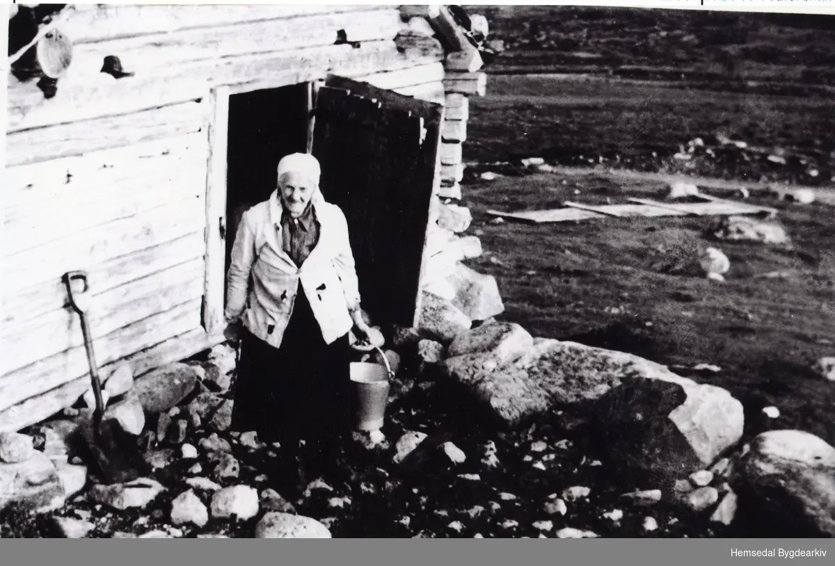 Margrethe Fekene med mjølkeringja i fjøsdøra på stølen i Mørkedalen i Hemsedal, ca. 1940