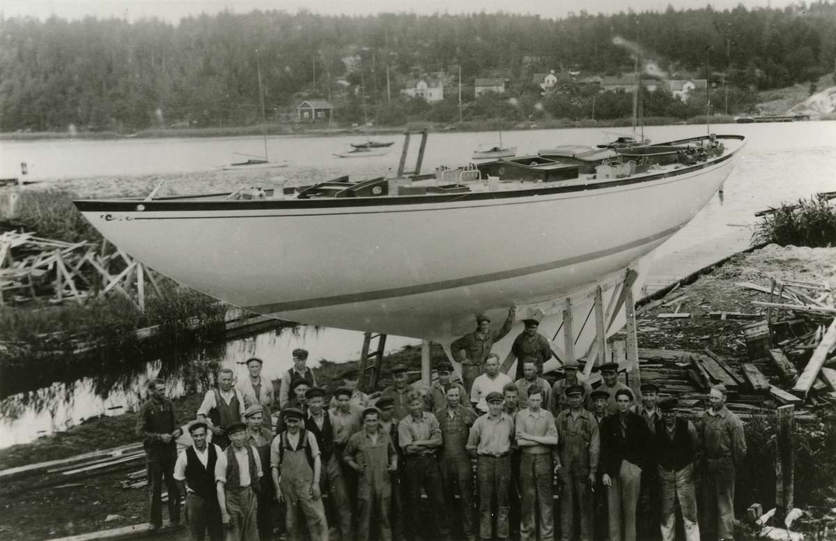 Sjösättning av havskryssaren Glädja vid Holms varv i Gamleby, omkring 1938. Varvsarbetarna samlade framför båten. Byggd för export till USA.