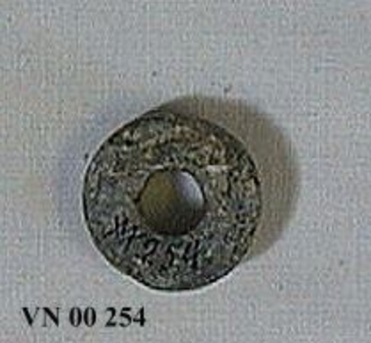 00 254. Gåva av J. Svedberg 4/6 1864.

Sländtrissa av täljsten. Regelbundet rund form. Plan över och undersida, som dock är vittrade. Ena sidan skadad. Diam. 3,2 cm. H. 1 cm.

Från Vänersborgs Läroverks samling. Till Vänersborgs museum 1886.