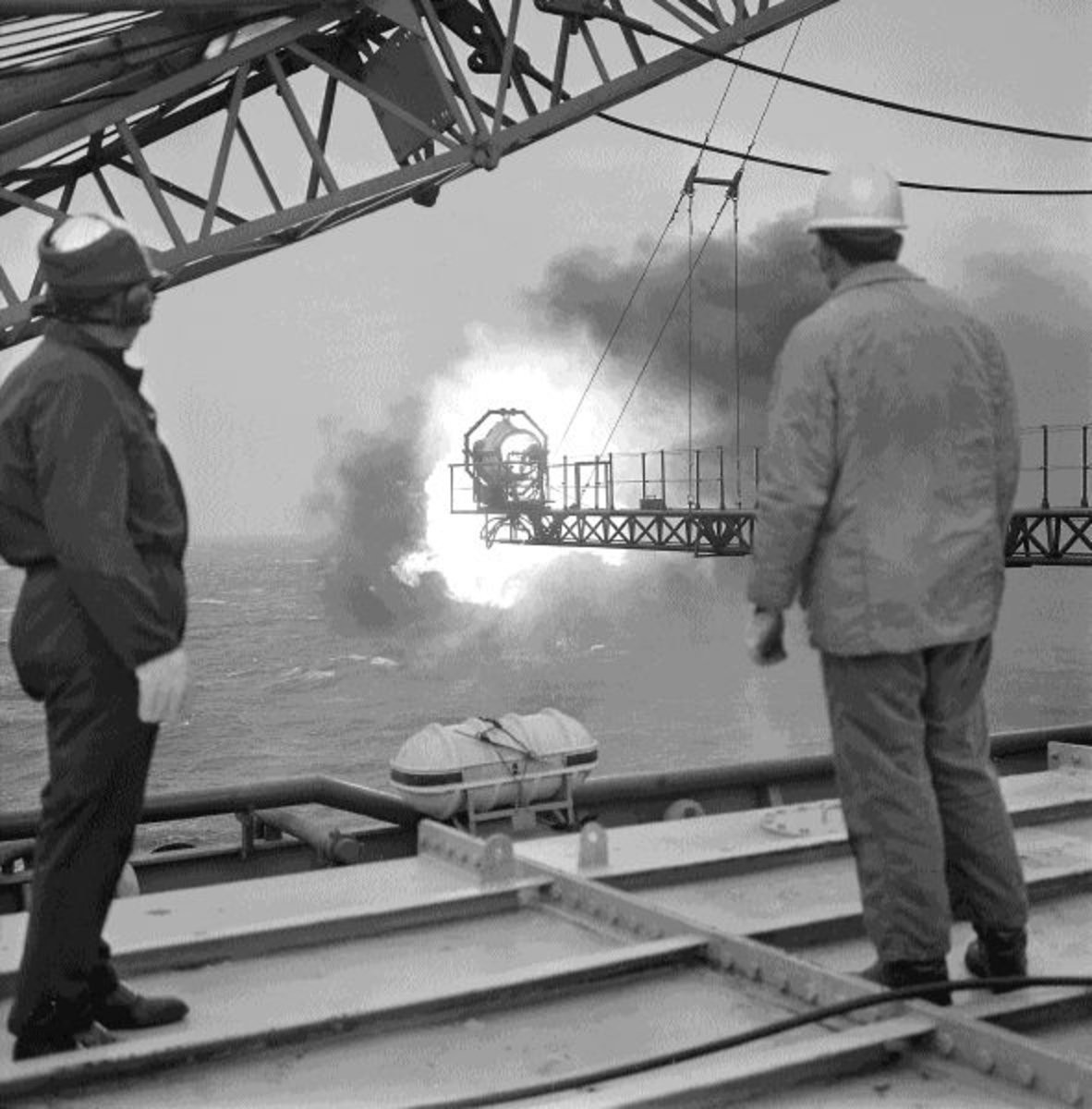 To menn studerer en flammebom på boreplattformen "Gulftide".