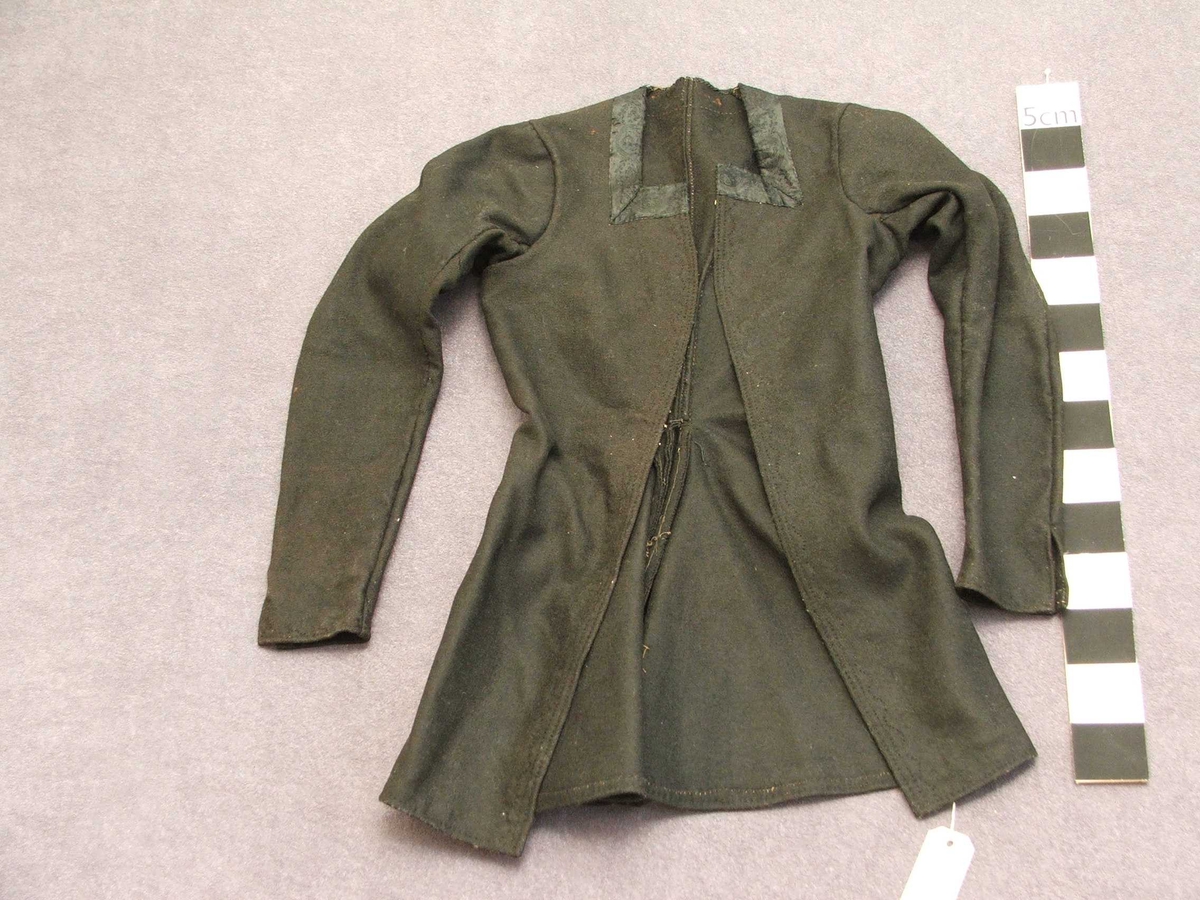 Svart blomstra silkeaktig band på
kragen. Rette og bølgeforma prydsaum på kvar side av opningen framme.