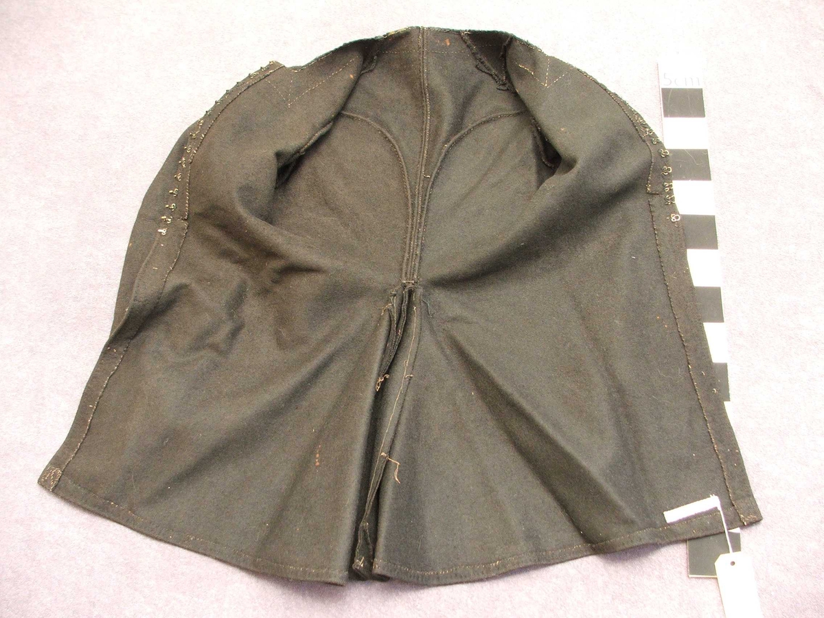 Svart blomstra silkeaktig band på
kragen. Rette og bølgeforma prydsaum på kvar side av opningen framme.