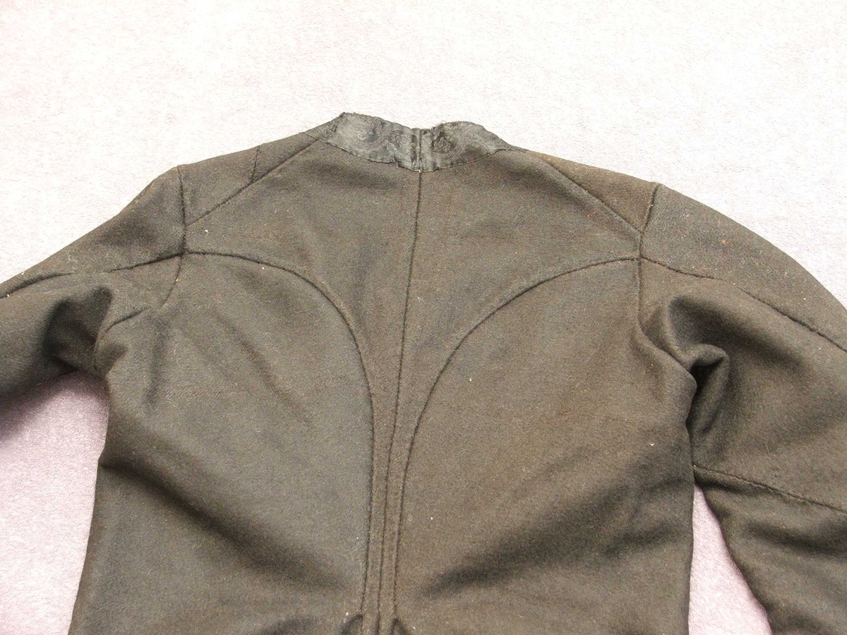 Svart blomstra silkeaktig band på
kragen. Rette og bølgeforma prydsaum på kvar side av opningen framme.