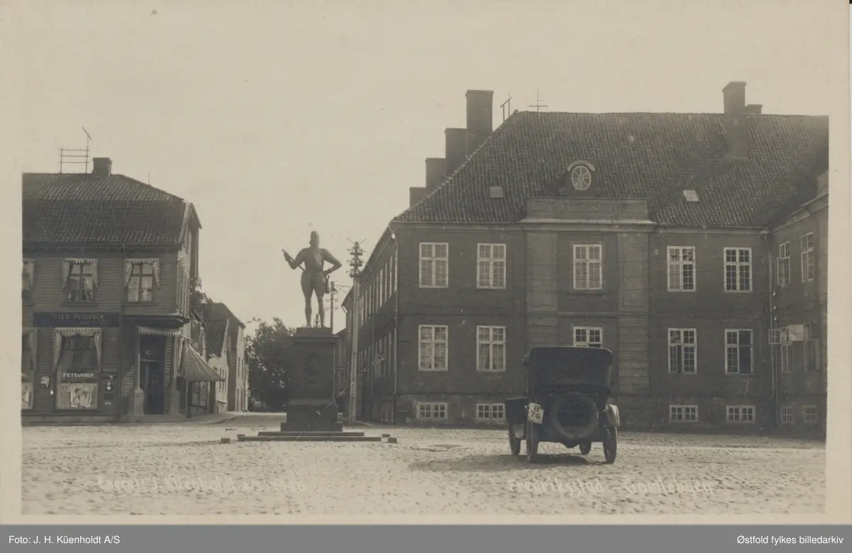 Infanterikasernen på torget i Gamlebyen i Fredrikstad, med statue av Fredrik den II og en bil av merket Dodge, tilhørende drosjeeier Erling Larsen, Elvehøy.  
Infanterikasernen ble tatt i bruk i 1788 og er enestående i arkitektur, bygd etter det kalendriske system med 4 porter, 12 piper, 52 værelser, 365 vinduer, 24 ruter OSV.

Bilen er en Dodge HK 30/35 med kjennetegn B-76. Drosjeier Erling Larsen eide bilen i 1922.