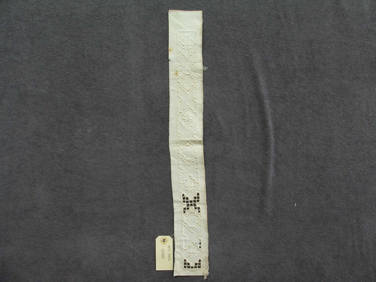 Byrjinga på broderi. Kvitsaum, holsaum. Ein kan sjå korleis holsaumen er gjort.