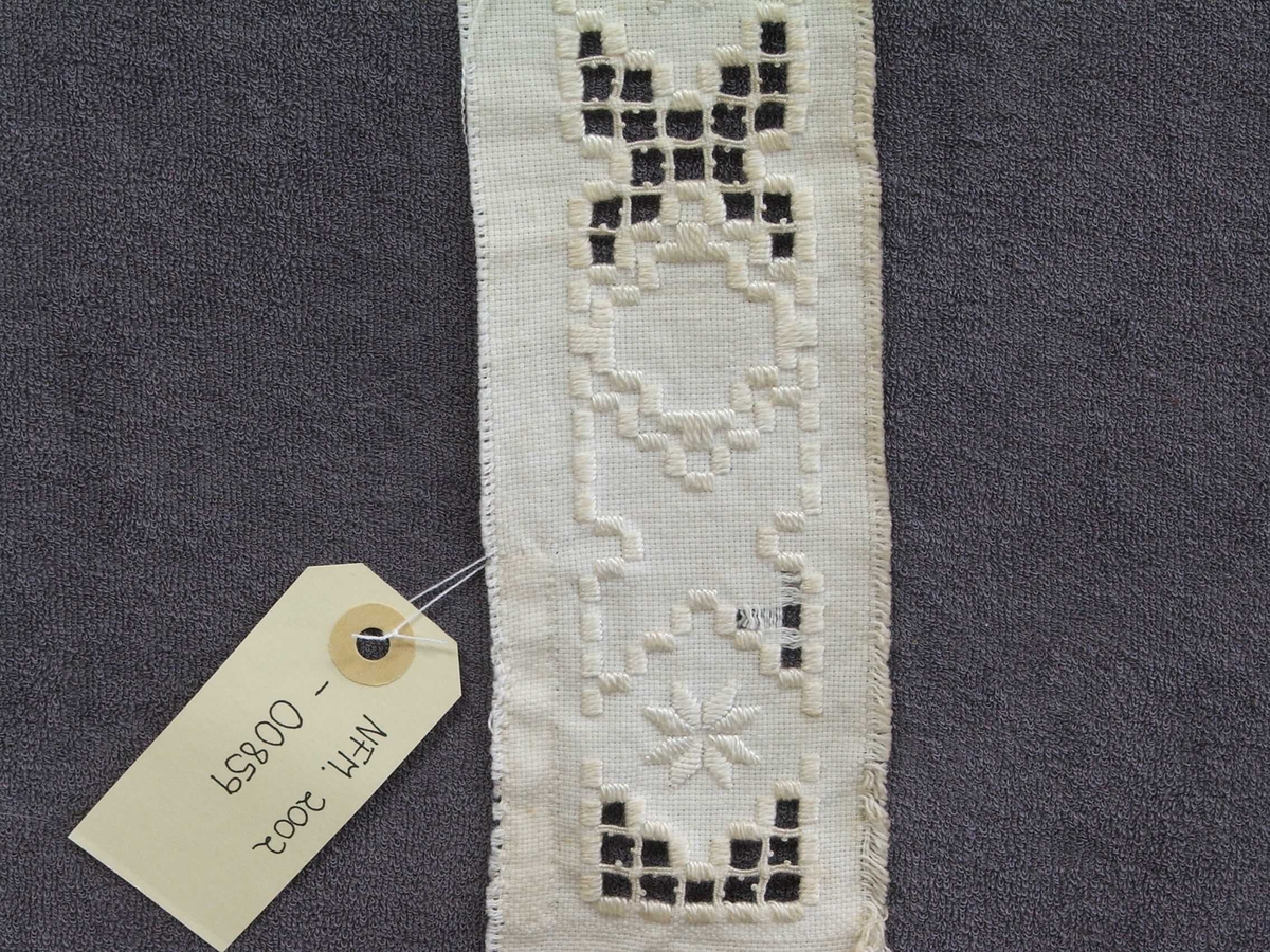 Byrjinga på broderi. Kvitsaum, holsaum. Ein kan sjå korleis holsaumen er gjort.