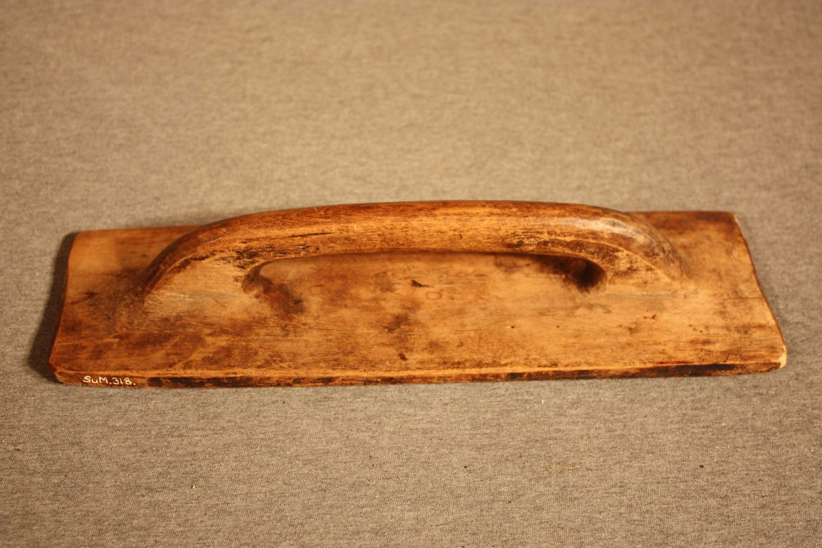 Form: rektangulær fjøl med rifla underside og handtak på oversida
