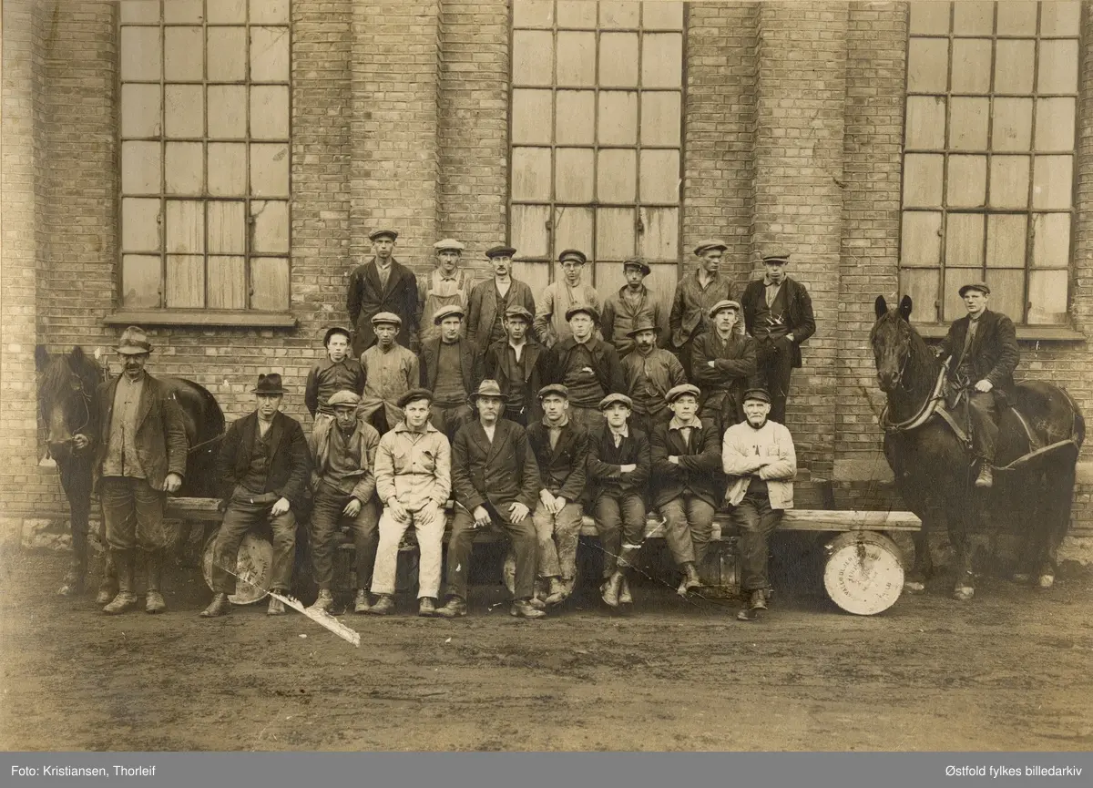 Arbeidsmannskap fra Greåker Cellulosefabrikk, før 1924. 
Til venstre Kristian Stang  (1865-1941) med hest, til høyre Karl Stang på hest. De var brødre.
Foreldre var Kristian og Adolfine Hansdatter Torstensen (ifølge folketelling 1900 for Tune). 
På tønnene står det Valle Oljeraffineri.

I e-post fra Arne Berger 1.11.2001: "Jeg tror ikke det kan være riktig at mannen til venstre med hest er Torstein Stang. Det må være hans far Kristian Torstensen f. 1865 som står der. Om hans sønn Torstein er med på bildet vet jeg ikke. Han med bart til venstre for Karl på hesteryggen kan være hans bror Hans født 1896.


I folketellingen for Tune 1900 heter Kristian Torstensens sønner Kristiansen. Kristian kommer fra Stang i øvre Tune. Stang er Kristian og hans families etternavn.
Karin L. Kristiansen skriver ( 2015):

Mannen med hest til venstre i bildet er Kristian Stang, født på Greåker 22.09.1865, død samme sted 17.02.1941. Han hadde 4 hester i fast utleie til Greåker Cellulosefabrik. Det hevdes at den andre mannen på hest er hans sønn Karl. Karl Stang er født 17.06.1908 og kan være for ung til det dersom bildet f.eks er tatt i 1920. Karl og broren Hans Arthur Stang var veldig like på bilder fra ungdommen. Hans Arthur var født 17.09.1896. Det er derfor mer trolig at det er han.                             Kristian Stang var sønn av Tosten Andersen. Ved folketellingen for Tune 1910 står han med navnet Torstensen. Hans kone Adolfine f 10.05.1869 (datter av Hans Andersen) står med slektsnavnet Hansdatter. Barna står med slektsnavn Kristiansen/Kristiansdatter. Familien hadde da allerede tatt slektsnavnet Stang. Parets eldste datter bodde i Kristiania i 1910 og står der med navnet Asta Katrine Stang. På landsbygda holdt tellerne på systemet med å benytte fars fornavn som etternavn på barna. Men Kristian og Adolfine valgte å ta navnet Stang da Kristians far, Tosten, var født og oppvokst på Stang i Tune. Folkeregister ble opprettet i Tune i 1943.