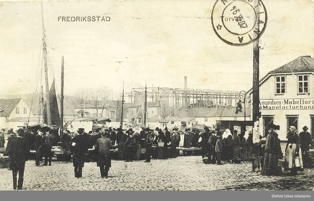 Torget i Fredrikstad fra prospektkort stemplet 1907.
Utsikt over mot Kråkerøy.
Amundsens Møbelforretning og Manufakturhandel ligger i enden av torget.

Fiskebasarene ble bygd i 1890 og ligger utenfor venstre bildekant. FMV i bakgrunnen med et rammeverk rundt stedet der båtene ble bygd.