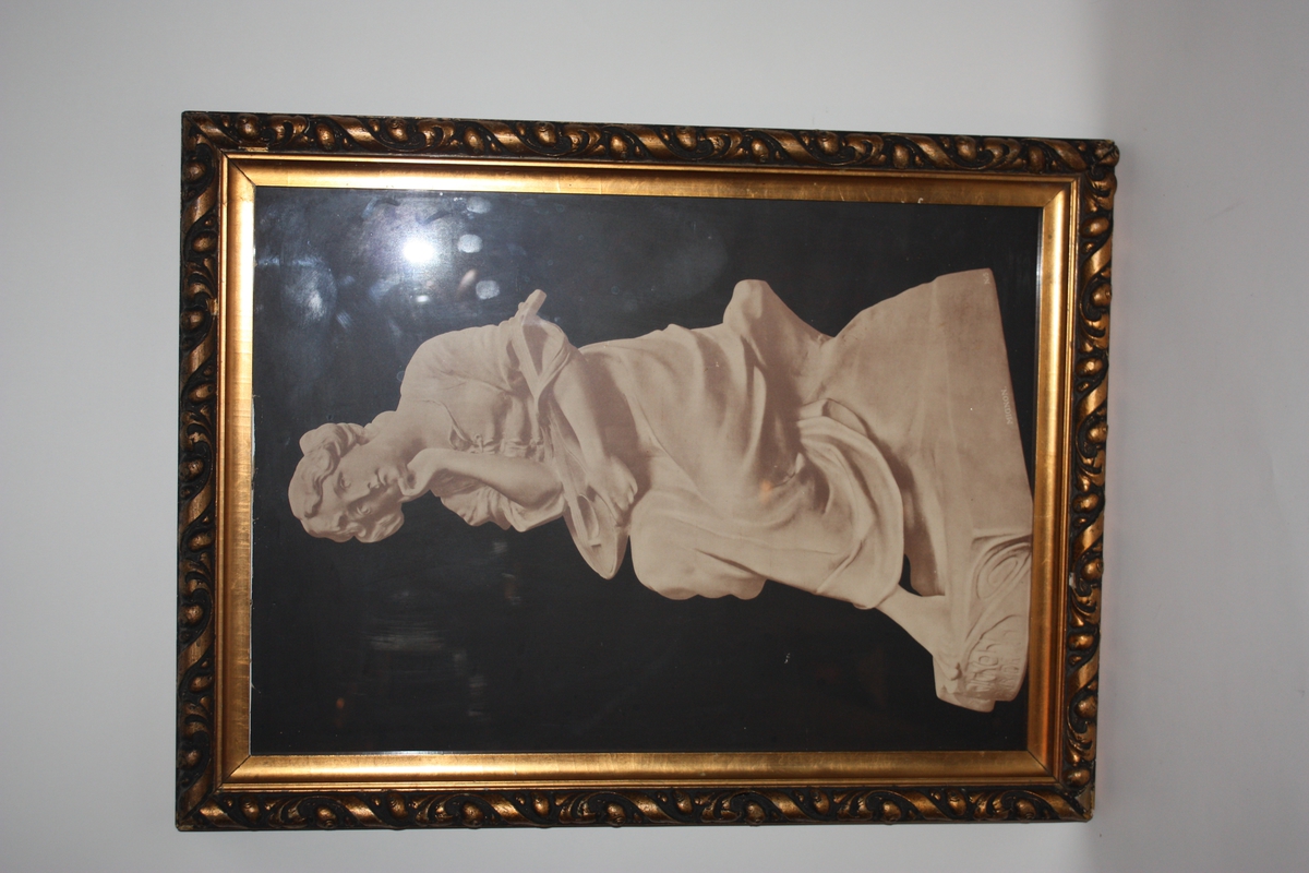 Kvit statue av ung kvinne med eit strengeinstrument i fanget. i fanget. Står på ein sokkel. Svart bakgrunn. Kan vere musen (skytsgudinna) for song og musikk, Terpsikhore, med lyra si.