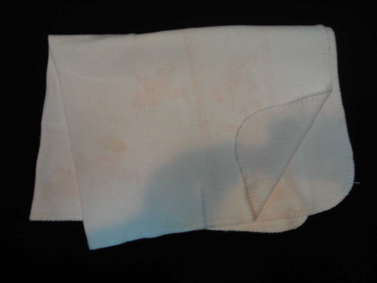 Teppet er kvitt på den eine og rosa på den andre sida. På den rosa sida er kvite bamsar, på den kvite sida er rosa bamsar.