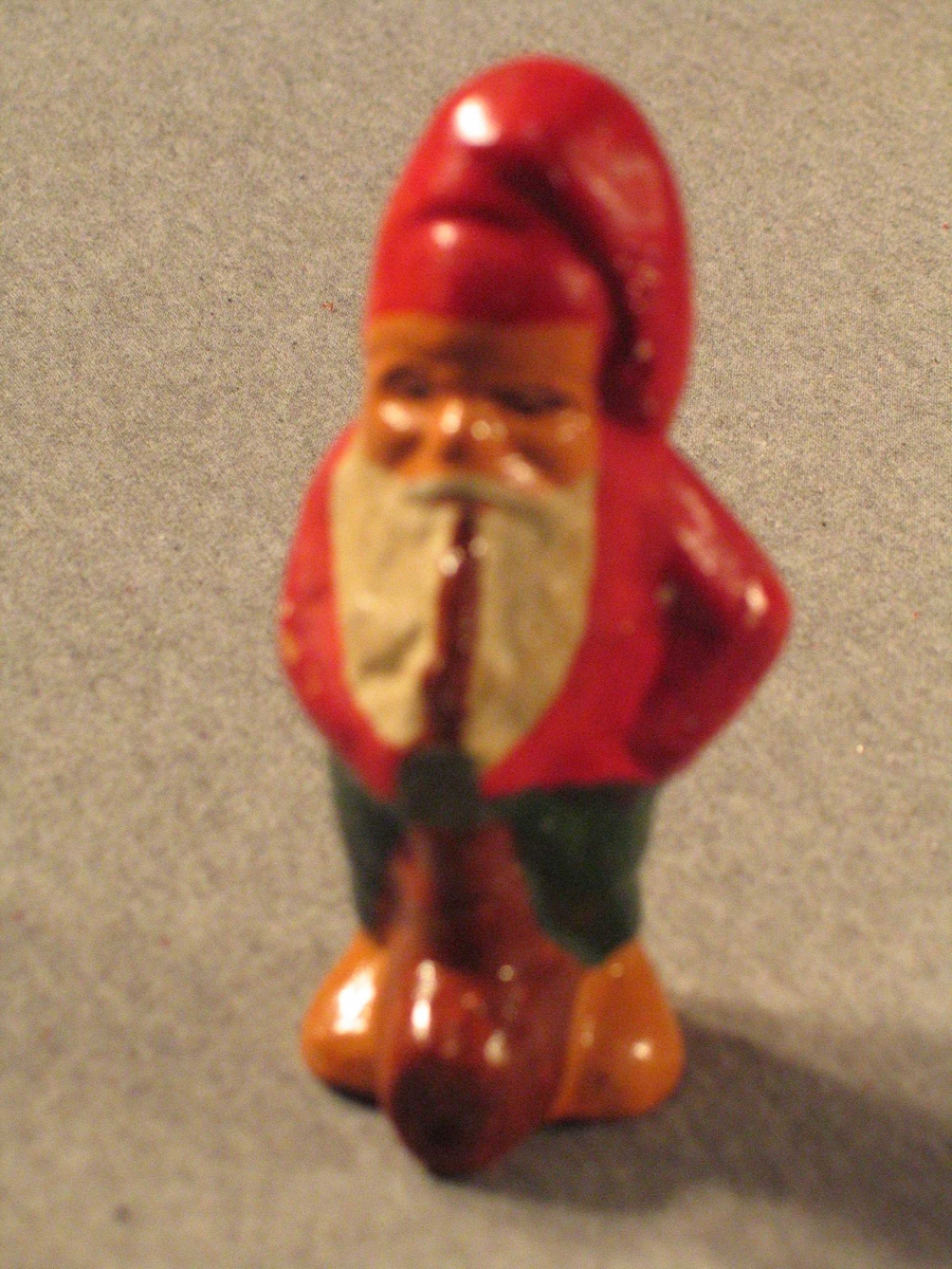 Nisse som står og røyker på ei fotsid pipe.