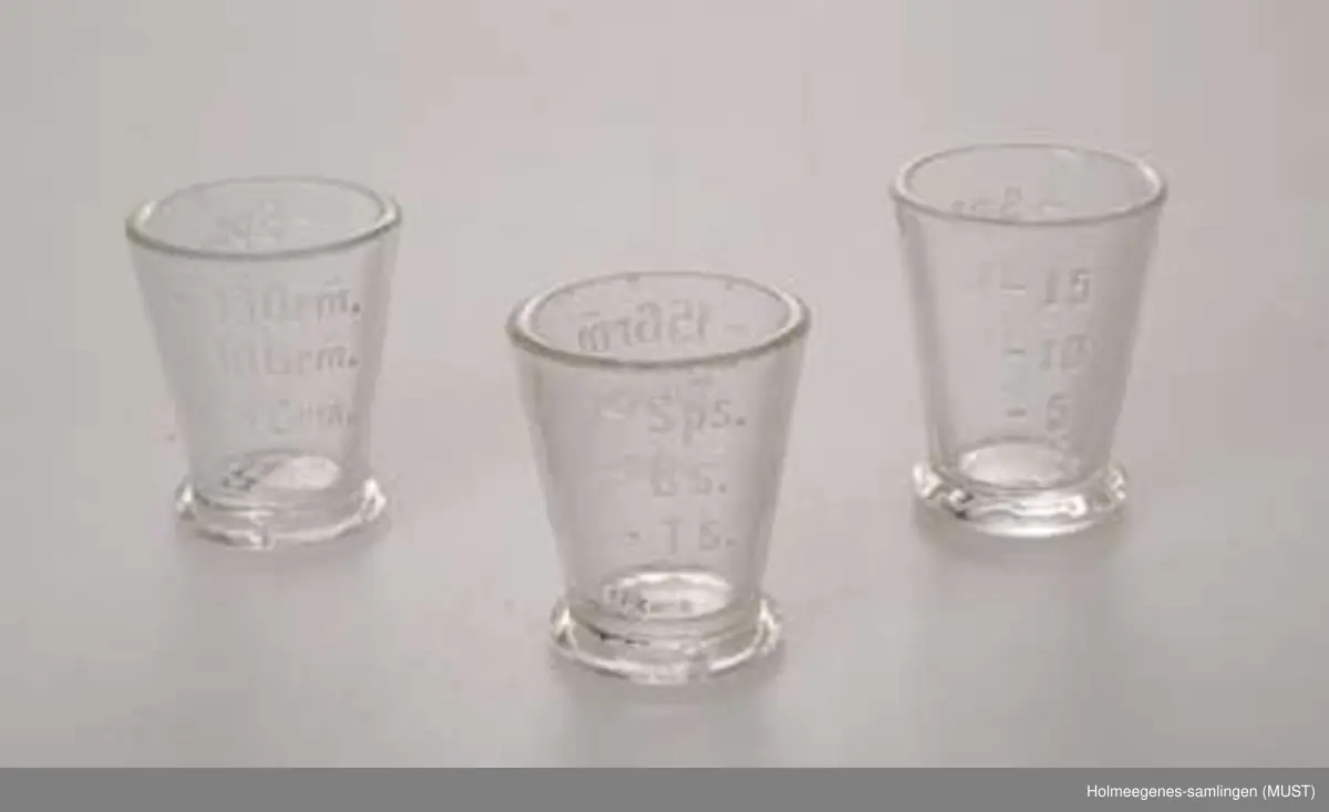 Tre små målebeger av glass. Måleenhetene er 5-10-16 gram, og teskje, barneskje og spiseskje.