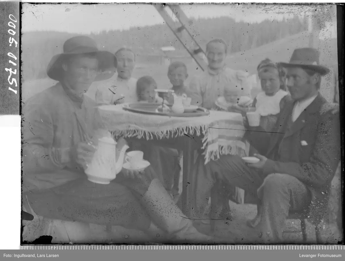 Gruppebilde av to menn, to kvinner og fire barn rundt et kaffebord.