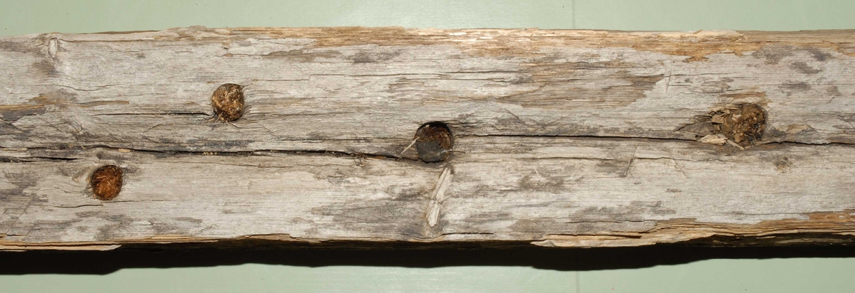 Kjøl til sydd båt utarbeidet av ett stykke tre. Det er hull til treplugger og sømhull med røtter på den ene siden. Den ene kortsiden skråner lett opp.
