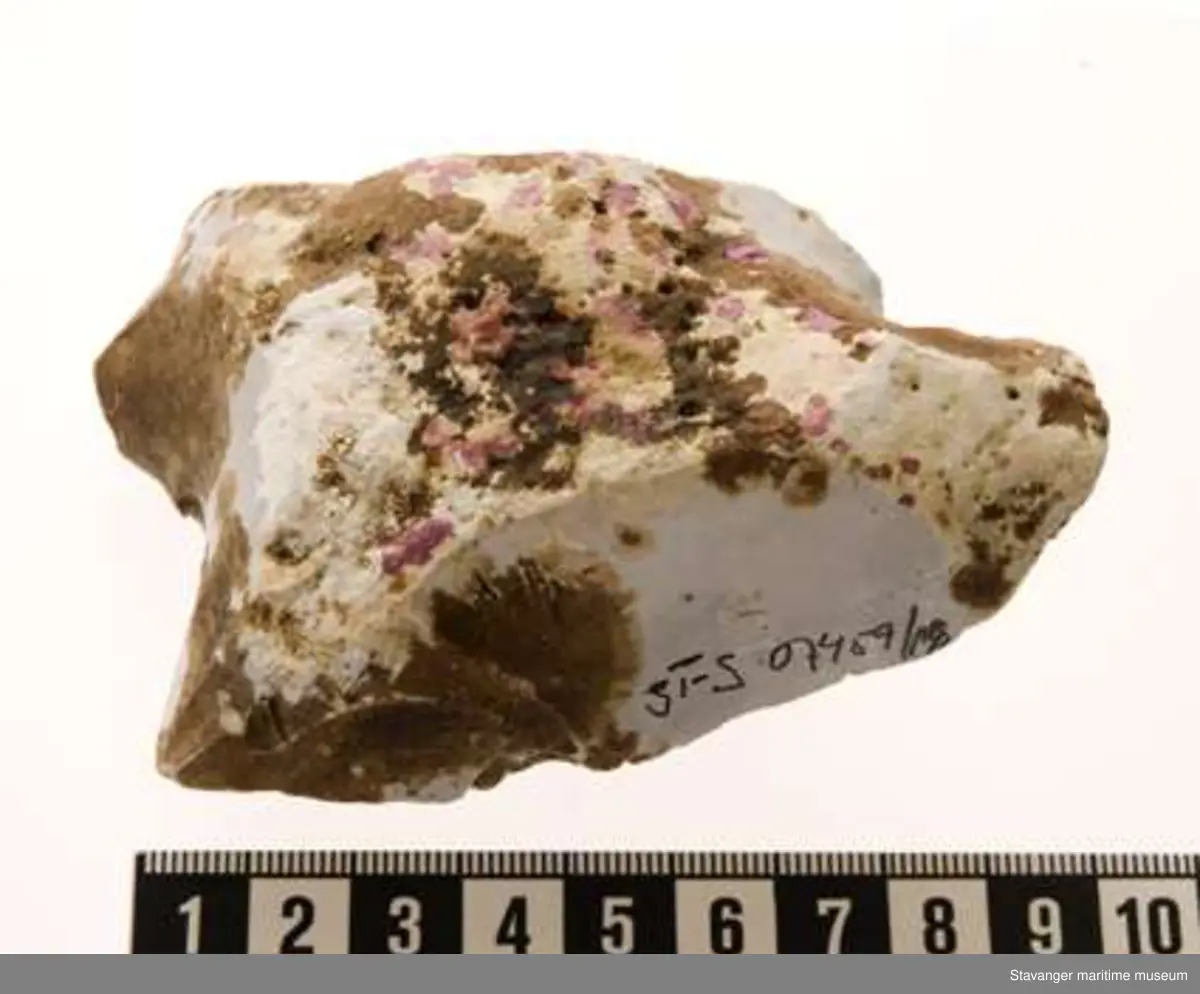 Flintknoll med gråhvit kjerne. Kalkoverflate med brune og røde flekker. 