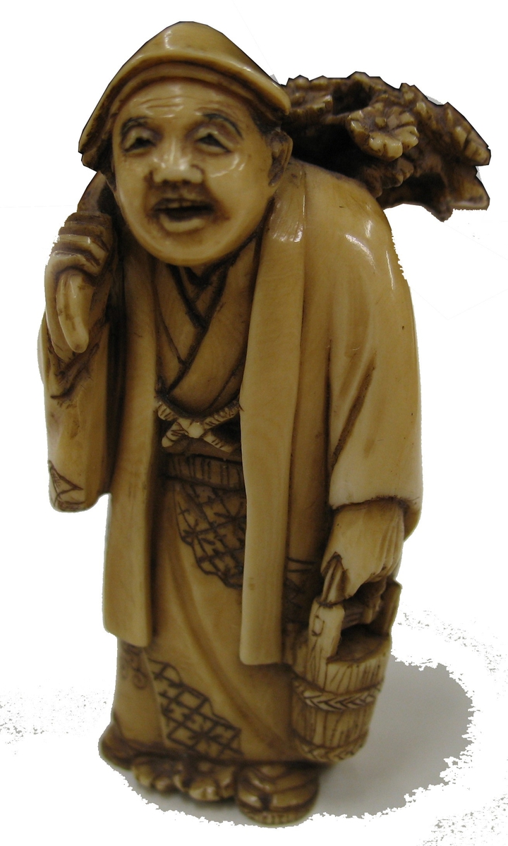15 368:066: Netsuke (man med växt på ryggen).
En netuske är en form av miniatyrskulpterad knapp i olika material.  Eftersom den traditionella japanska dräkten saknade fickor så fick denna knapp både en praktisk och prydande funktion som mothåll till hängande föremål som bars vid bältet.