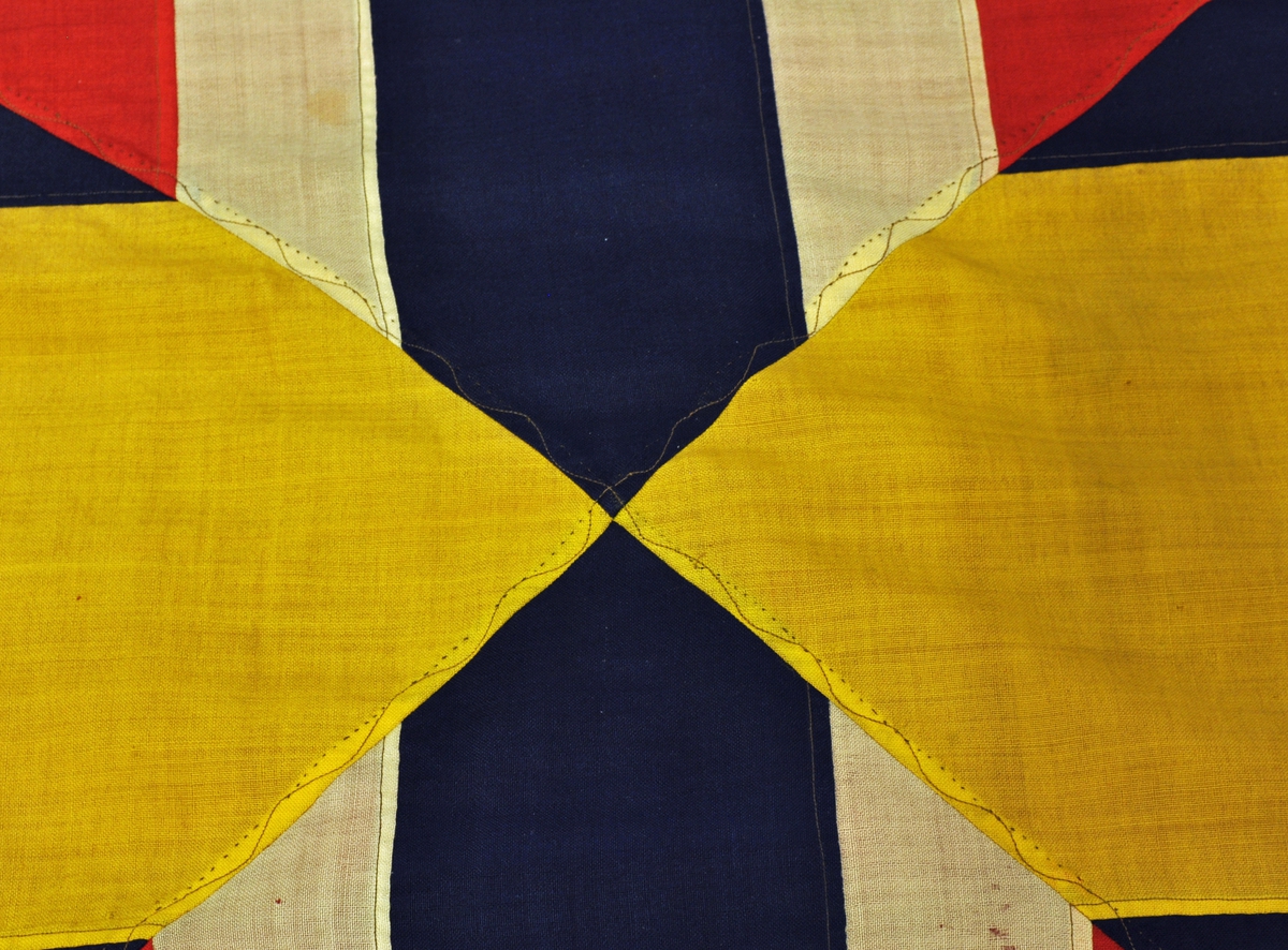 Norsk flagg med unionsmerke ("sildesalat). Unionsmerket er applikert på en rød rute øverst i høyre hjørne.
Det er påmontert  kanalgang(5,5cm) for feste av tau. Inne i kanalgangen er det antakeligvis tau av hamp. I enden av kanalgangen er det montert på en festeanordning av metall.