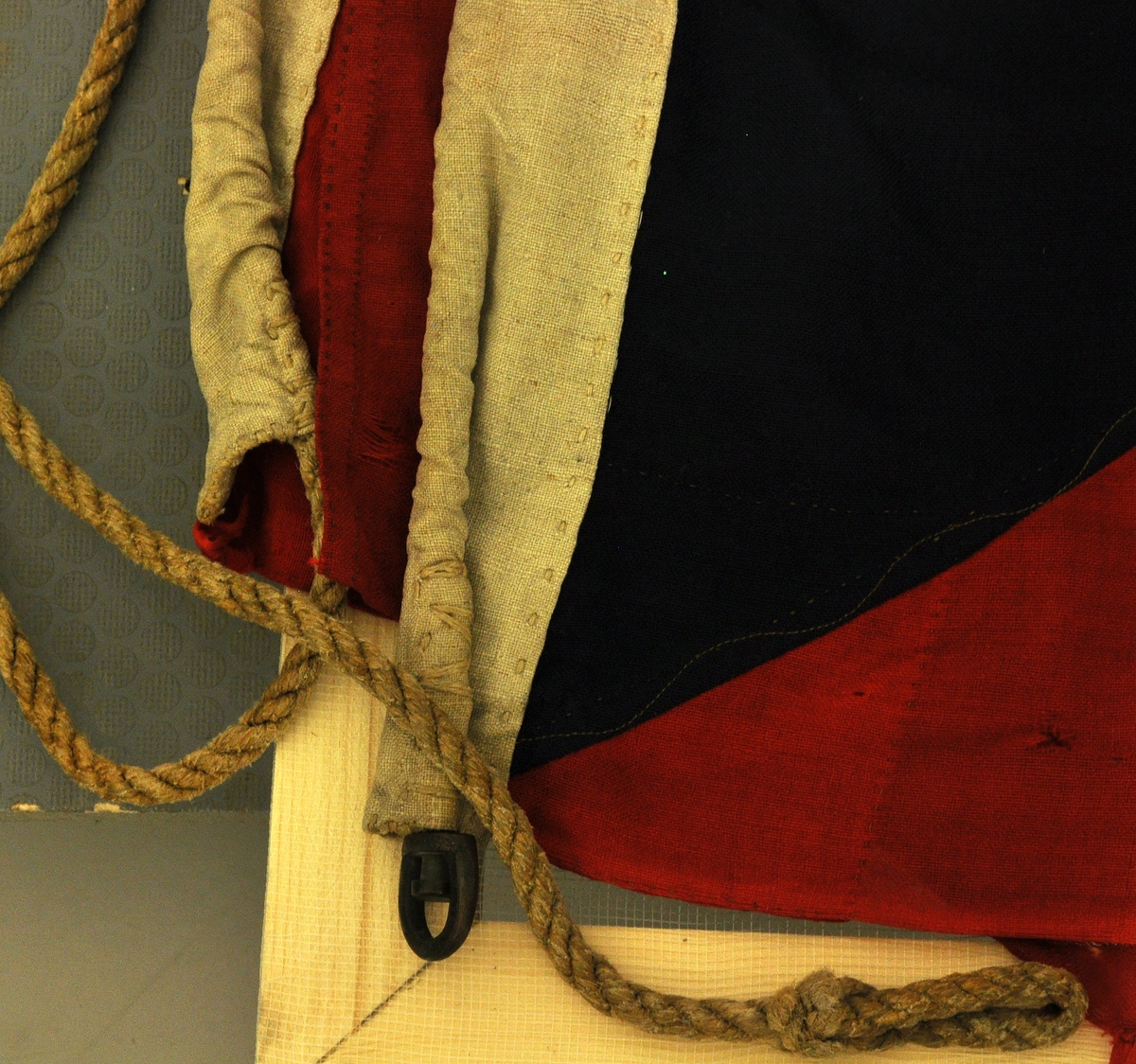 Norsk flagg med unionsmerke ("sildesalat). Unionsmerket er applikert på en rød rute øverst i høyre hjørne.
Det er påmontert  kanalgang(5,5cm) for feste av tau. Inne i kanalgangen er det antakeligvis tau av hamp. I enden av kanalgangen er det montert på en festeanordning av metall.