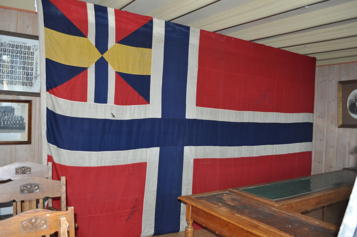 Norsk flagg med unionsmerke ("sildesalat). Unionsmerket er applikert på en rød rute øverst i høyre hjørne.
Det er påmontert  kanalgang(5,5cm) for feste av tau. Inne i kanalgangen er det antakeligvis tau av hamp. I enden av kanalgangen er det montert på en festeanordning av metall.