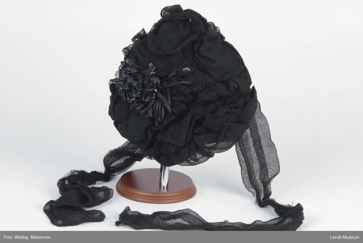 Form: draperinger av sort silkejersey og sort maskin-
