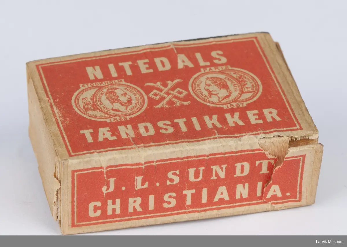 På lokket tekst og 2 mynter på hver side av et ornament med 