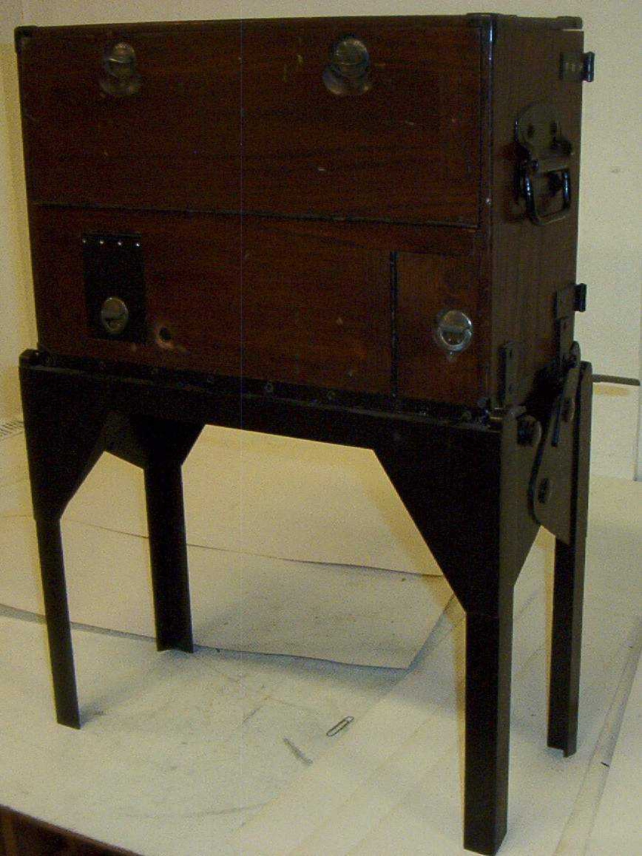 Telefonsentral (feltveksler) av eldre type med ledninger og plugger i grønn transportkasse på fire bein.