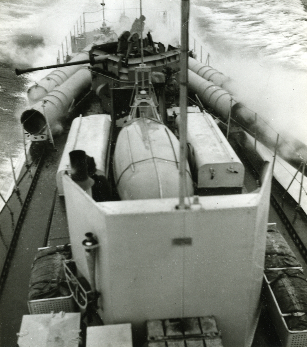 Foto visande däcksbild av en svensk torpedbåt av T 102-typ.
Aktra 40 mm kanonen samt 4 st. 53.3 cm. torpedtuber syns tydligt. En av babordstorpederna avlossas.