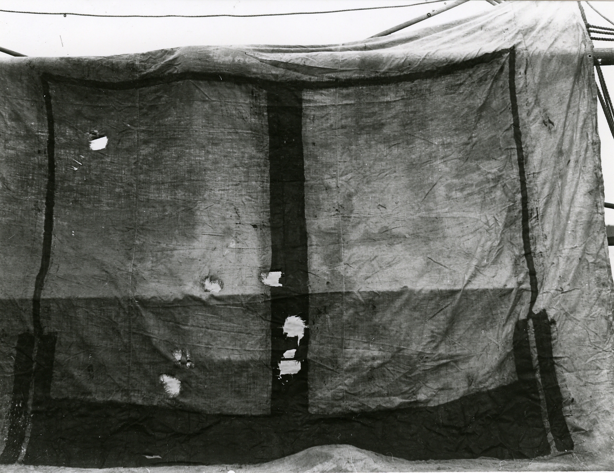 Presenning med markeringar och skotthål, troligen använd vid målskjutning.