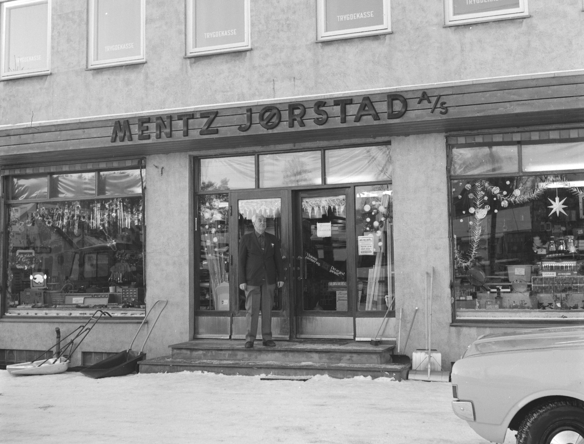 Mentz Jørstad AS, Jern og byggevareforretning i Nygata, Brumunddal. 
Juleutstilling, juletre. Bernhard Bjørnstad utenfor forretningen.