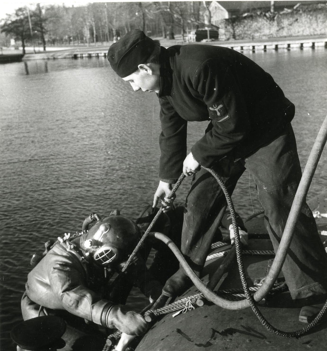 Dykarbete på ubåten Sjöormen vid Skeppsholmen 1949.
Tungdykare går ned vid ubåten.
