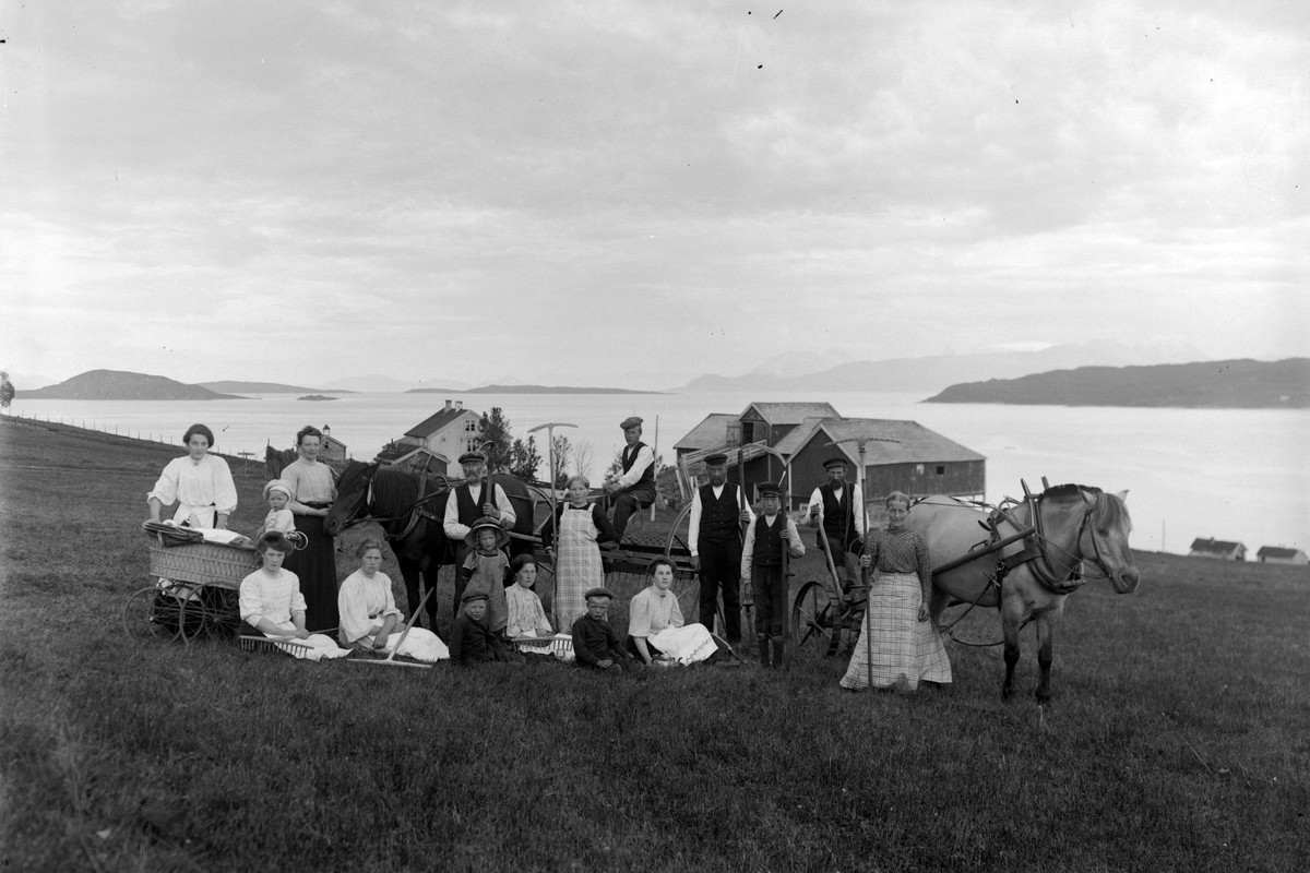 Gruppeportrett av arbeidsfolk og hester på Røkenes. Én av kvinnene til venstre har en barnevogn.