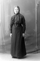 Studioportrett av en kvinne i en mørk kjole.