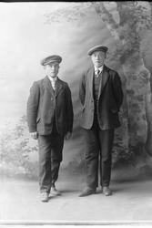 Studioportrett av to menn i helfigur.