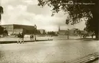 Stockholm. Vy från Skeppsholmen med två matroser i förgrunden, passagerarfartyg vid Skeppsbrokajen med Kungliga slottet i bakgrunden.