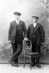 Studioportrett av to menn i helfigur.