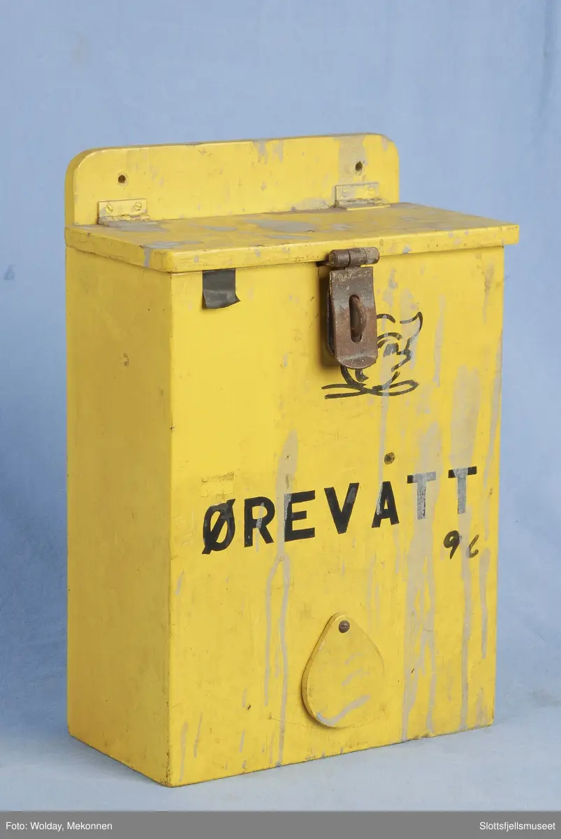 Kasse av tre, gulmalt; merket Ørevatt. Hull til å dra ut ørevatt av, i nederste del av kassen