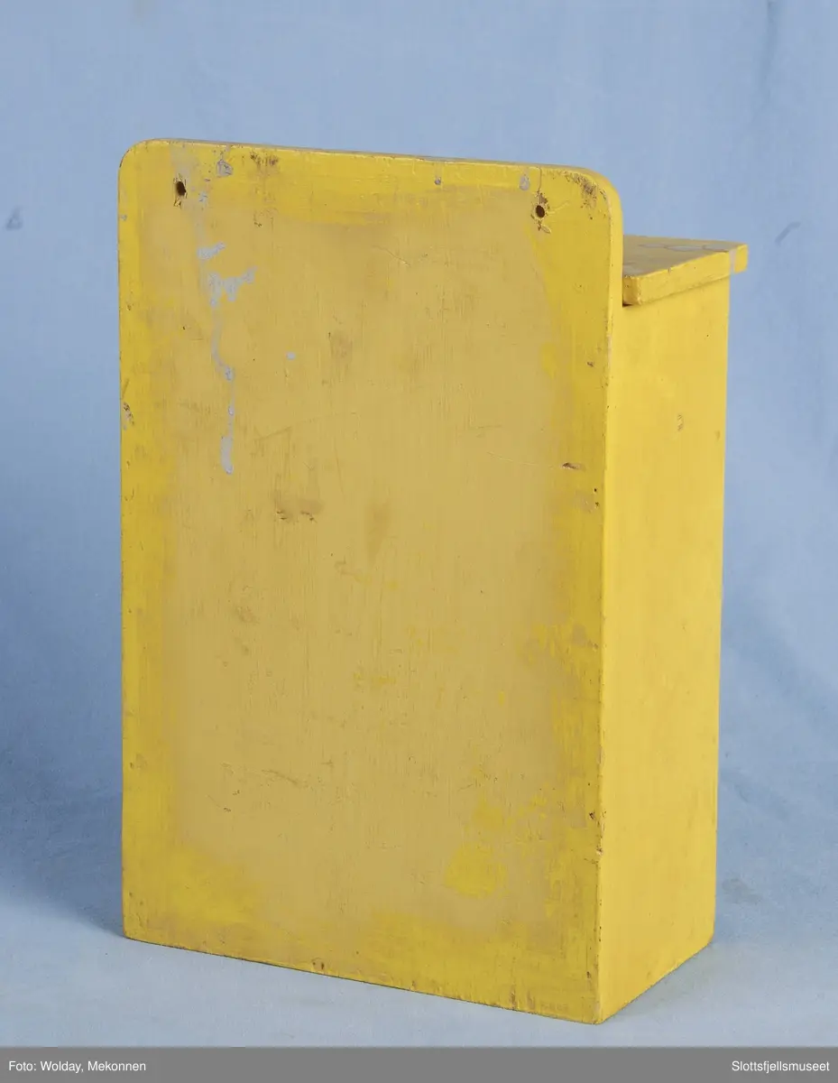 Kasse av tre, gulmalt; merket Ørevatt. Hull til å dra ut ørevatt av, i nederste del av kassen