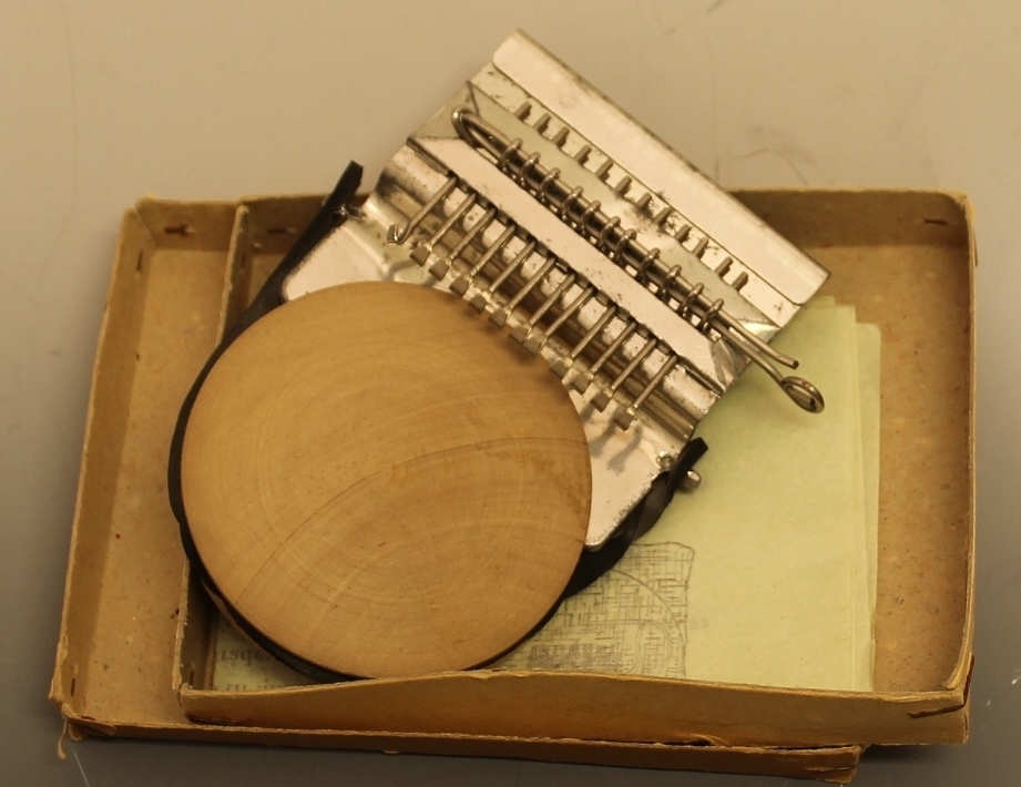 Rektangulær eske med "Stopper'n" og bruksanvisning oppi. brukt til å stoppe hull i strømper, sokker og alle strikket plagg.