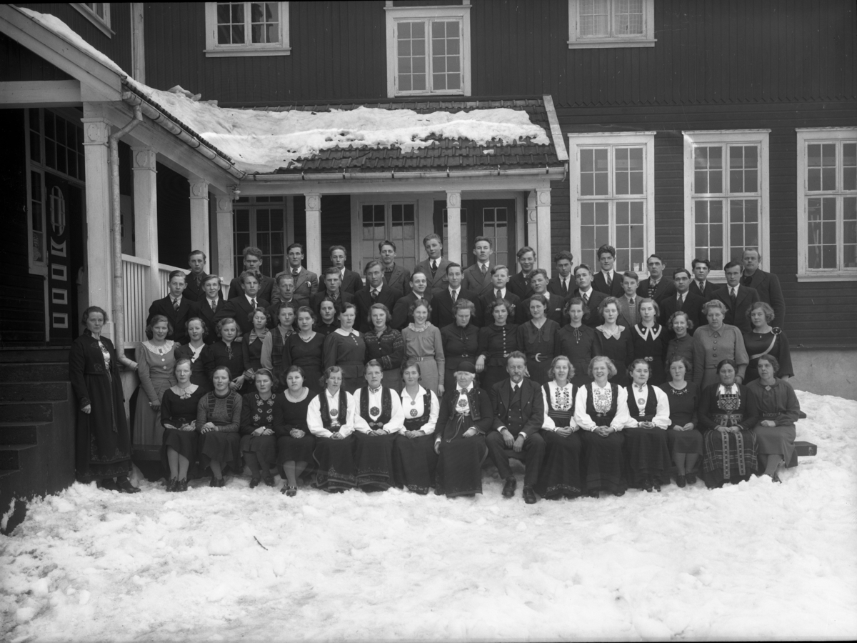 Utendørs gruppebilde av unge mennesker. Folkehøgskulen Utsund, Kviteseid. Jacob Naadland og frue i midten.