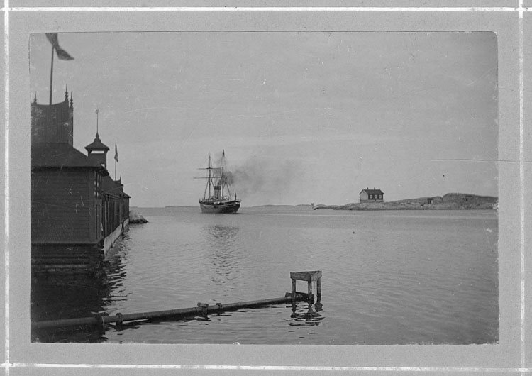 Handskrivet på kopian: "Marstrand, norra inloppert. T.h. fyrvaktarhus med inbyggd fyr. 
T.v. kallbadhuset omkr. 1890".