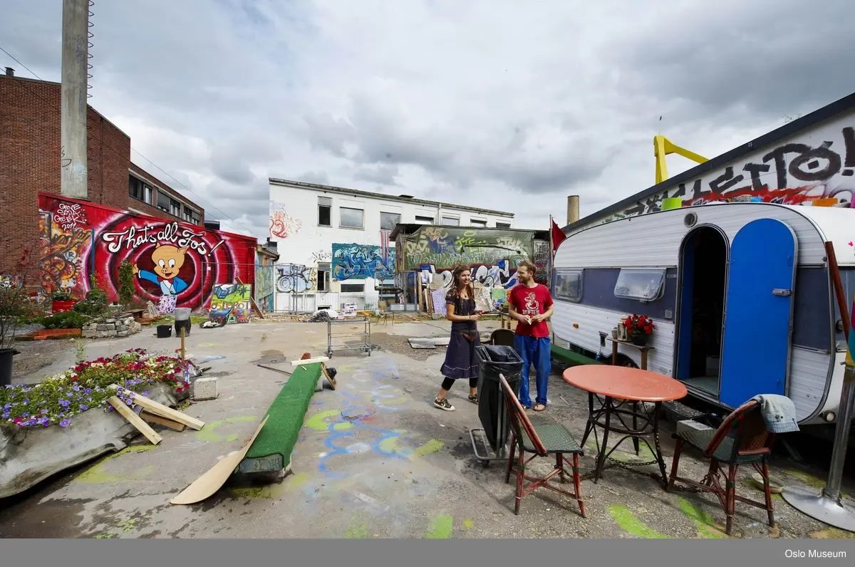 Hausmania, eksteriør, indre gårdsrom, campingvogn, blomster, grønnsaksdyrking, kvinne, mann, bord, stoler.