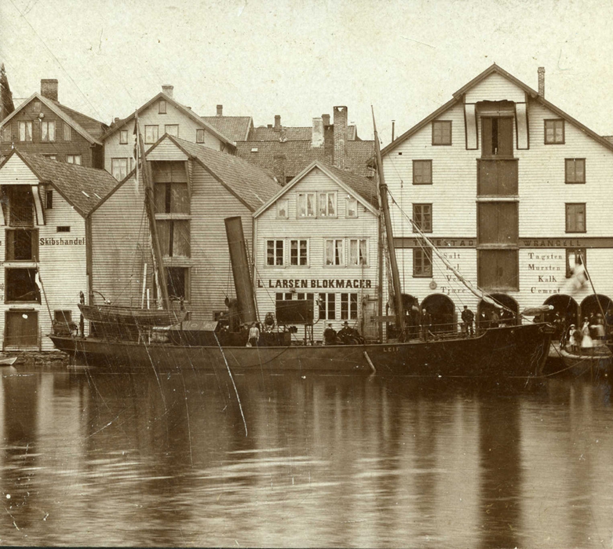 Sjø i forgrunnen.  Til kai ligger "Leif" med sjøhus i bakgrunnen.
Smedasundet ved Wrangells kai. Hvalfanger "Leif" bygget i 1893. Sannsynligvis eiet av Wrangell. Se side 408 i R. Østensjø "Haigesund 1835 - 1895".