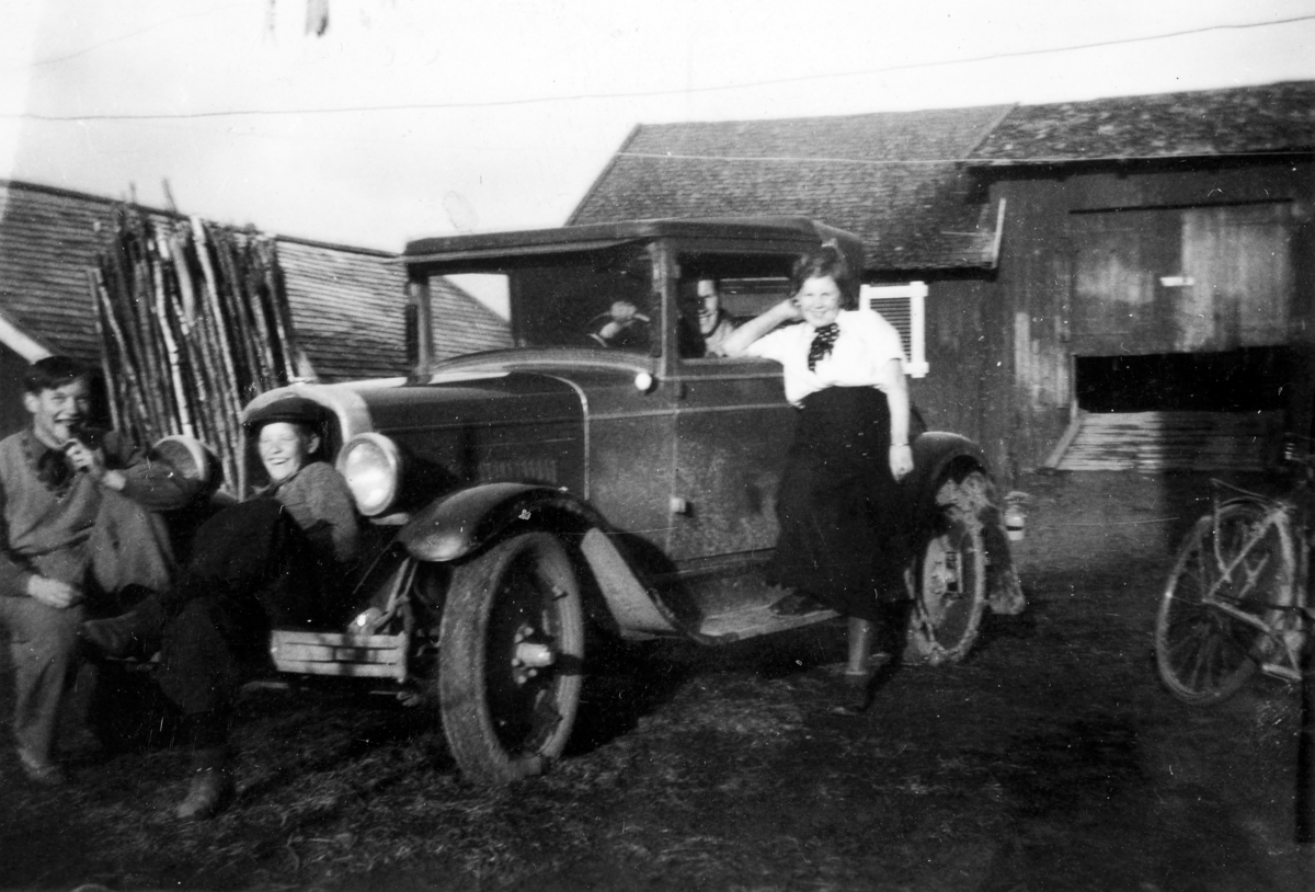 Gammel bil Coupe årsmodell 1926-1928, gårdstun, fire personer. Fra venstre: Sverre Tangen, Hallgeir Tangen, inni bilen: Arne Tangen, Helga Tangen. Ilseng, Stange.