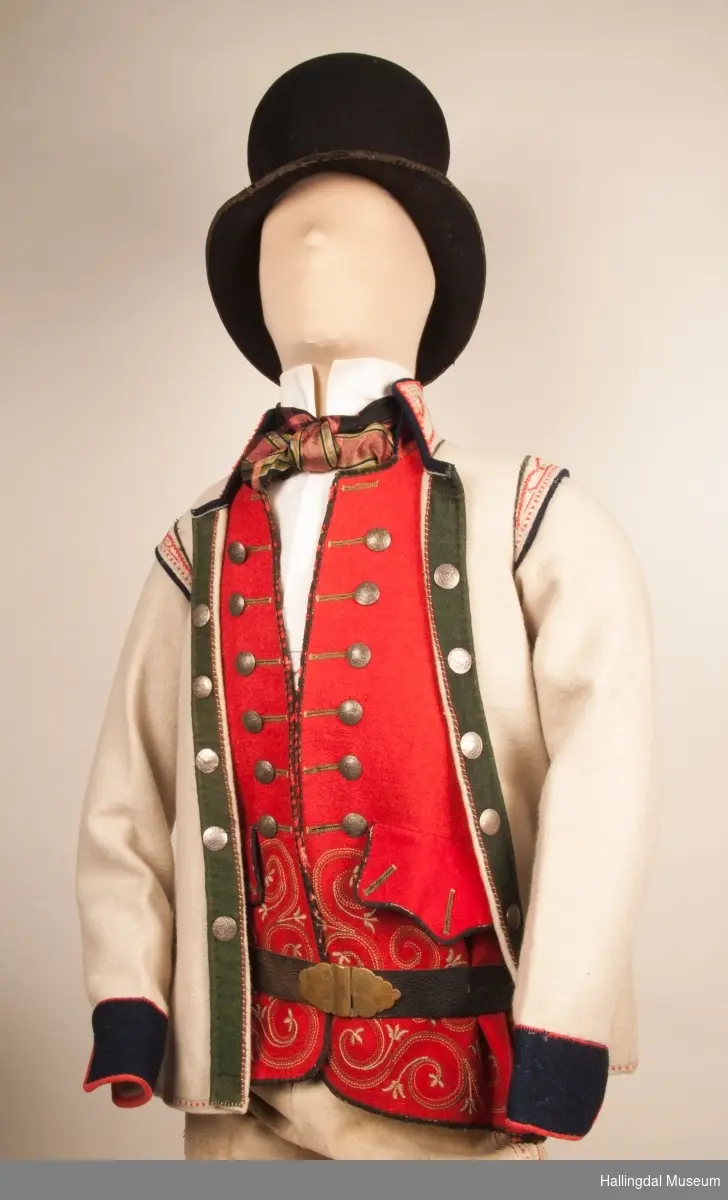 Brudgom fra Hallingdal ca. 1830. Brudgomsdrakten er satt sammen av mange plagg deriblant rød lang rød vest HFN 03616,kvit steglatrøye HFN 03615, høy hatt HFN 03086,  sokkeband HFN 01911 a-b,  knebukse HFN 2024, sko HFN 03124 a-b, skinnbelte HFN 01912, knesokker HFN 03618, kaste 03389 og silkesjal HFN 02004. Brudgommen har stått utstilt i den faste bunadutstillingen på Hallingdal Museum, Nesbyen fra 2009.