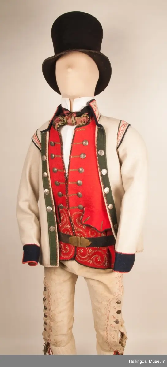 Brudgom fra Hallingdal ca. 1830. Brudgomsdrakten er satt sammen av mange plagg deriblant rød lang rød vest HFN 03616,kvit steglatrøye HFN 03615, høy hatt HFN 03086,  sokkeband HFN 01911 a-b,  knebukse HFN 2024, sko HFN 03124 a-b, skinnbelte HFN 01912, knesokker HFN 03618, kaste 03389 og silkesjal HFN 02004. Brudgommen har stått utstilt i den faste bunadutstillingen på Hallingdal Museum, Nesbyen fra 2009.