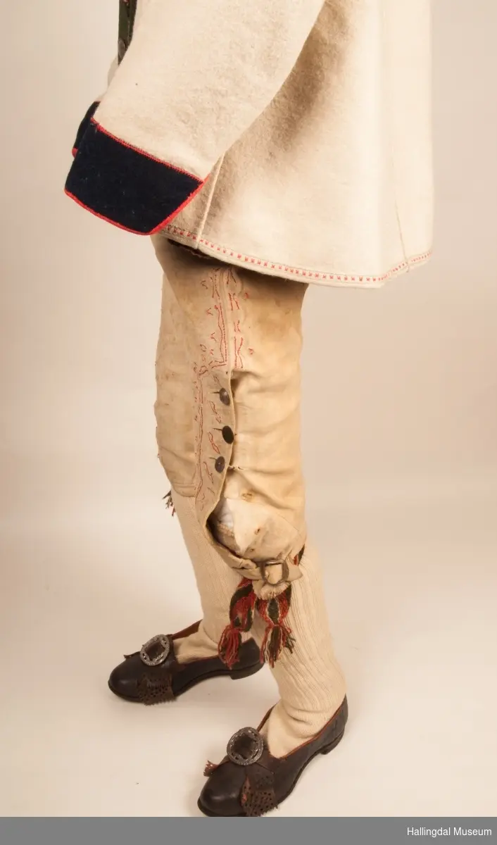 Brudgom fra Hallingdal ca. 1830. Brudgomsdrakten er satt sammen av mange plagg deriblant rød lang rød vest HFN 03616,kvit steglatrøye HFN 03615, høy hatt HFN 03086,  sokkeband HFN 01911 a-b,  knebukse HFN 2024, sko HFN 03124 a-b, skinnbelte HFN 01912, knesokker HFN 03618, kaste 03389 og silkesjal HFN 02004. Brudgommen har stått utstilt i den faste bunadutstillingen på Hallingdal Museum, Nesbyen fra 2009.