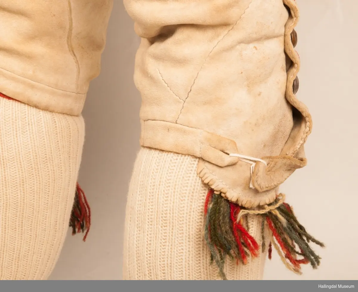 Brudgom fra Hallingdal ca. 1830. Brudgomsdrakten er satt sammen av mange plagg deriblant rød lang rød vest HFN 03616,kvit steglatrøye HFN 03615, høy hatt HFN 03086,  sokkeband HFN 01911 a-b,  knebukse HFN 2024, sko HFN 03124 a-b, skinnbelte HFN 01912, knesokker HFN 03618, kaste 03389 og silkesjal HFN 02004. Brudgommen har stått utstilt i den faste bunadutstillingen på Hallingdal Museum, Nesbyen fra 2009.